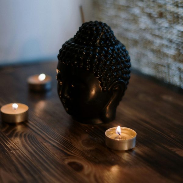 A serene setup with a Buddha head sculpture surrounded by soothing candlelight, perfect for relaxation.